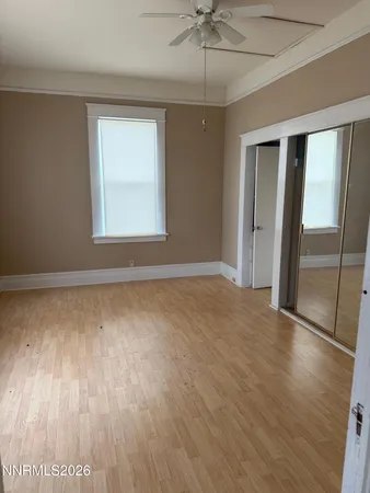 a view of an empty room with wooden floor and a window