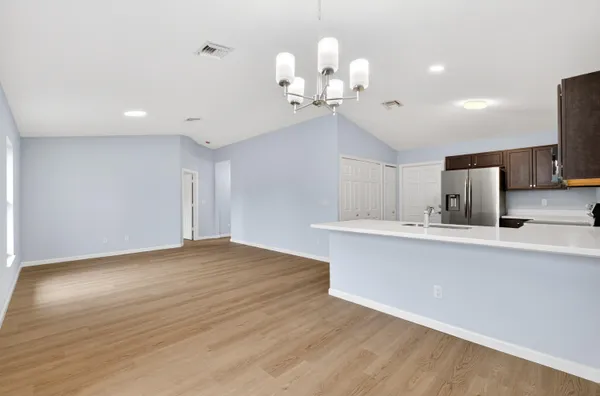 a view of a kitchen with a sink and chandelier stainless steel appliances