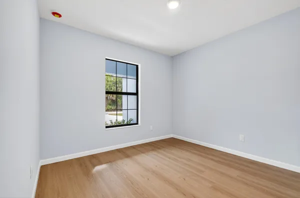 an empty room with wooden floor and windows