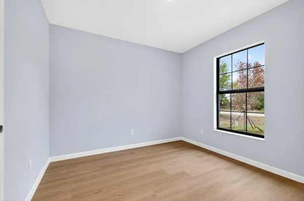 an empty room with wooden floor and windows