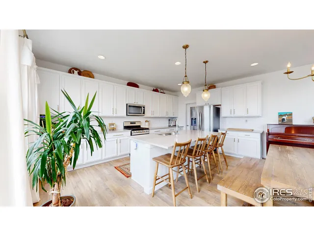 a living room with stainless steel appliances kitchen island a table and chairs in it