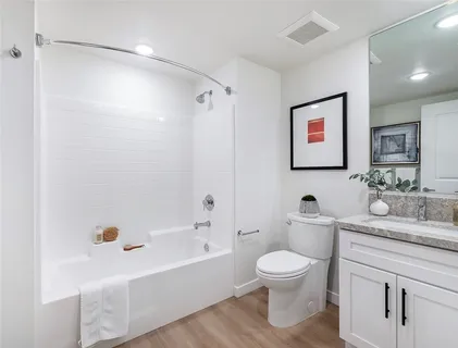 a bathroom with a toilet sink a mirror a bathtub and vanity