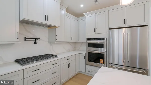 a large kitchen with a large counter top a sink stainless steel appliances and cabinets