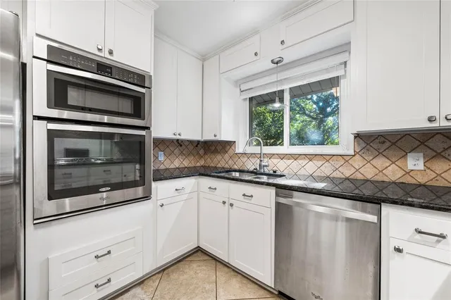 a kitchen with white cabinets and stainless steel appliances