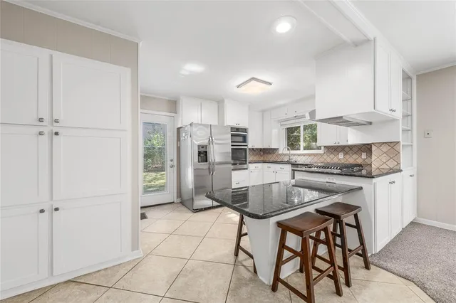 a kitchen with granite countertop white cabinets white appliances a sink and a counter top space