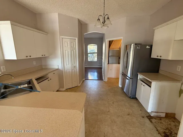 a view of a kitchen with a sink refrigerator and wooden floor