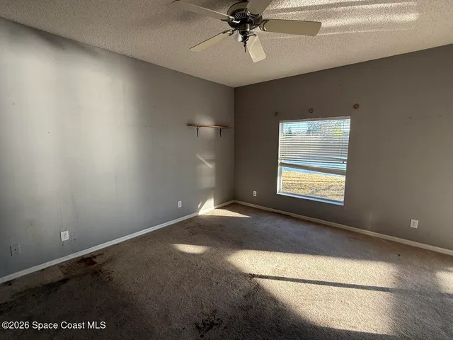 an empty room with windows and fan