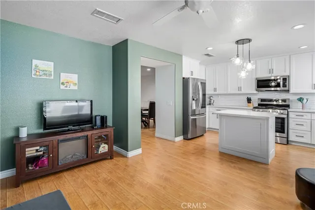 a living room with stainless steel appliances furniture and a flat screen tv