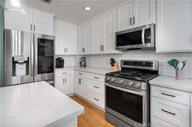 a kitchen with stainless steel appliances white cabinets white stove a microwave and a refrigerator