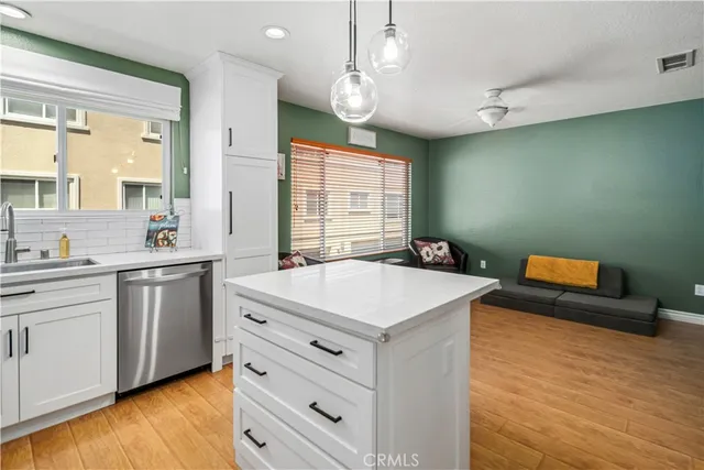 a kitchen with a sink dishwasher a stove and white countertops with wooden floor