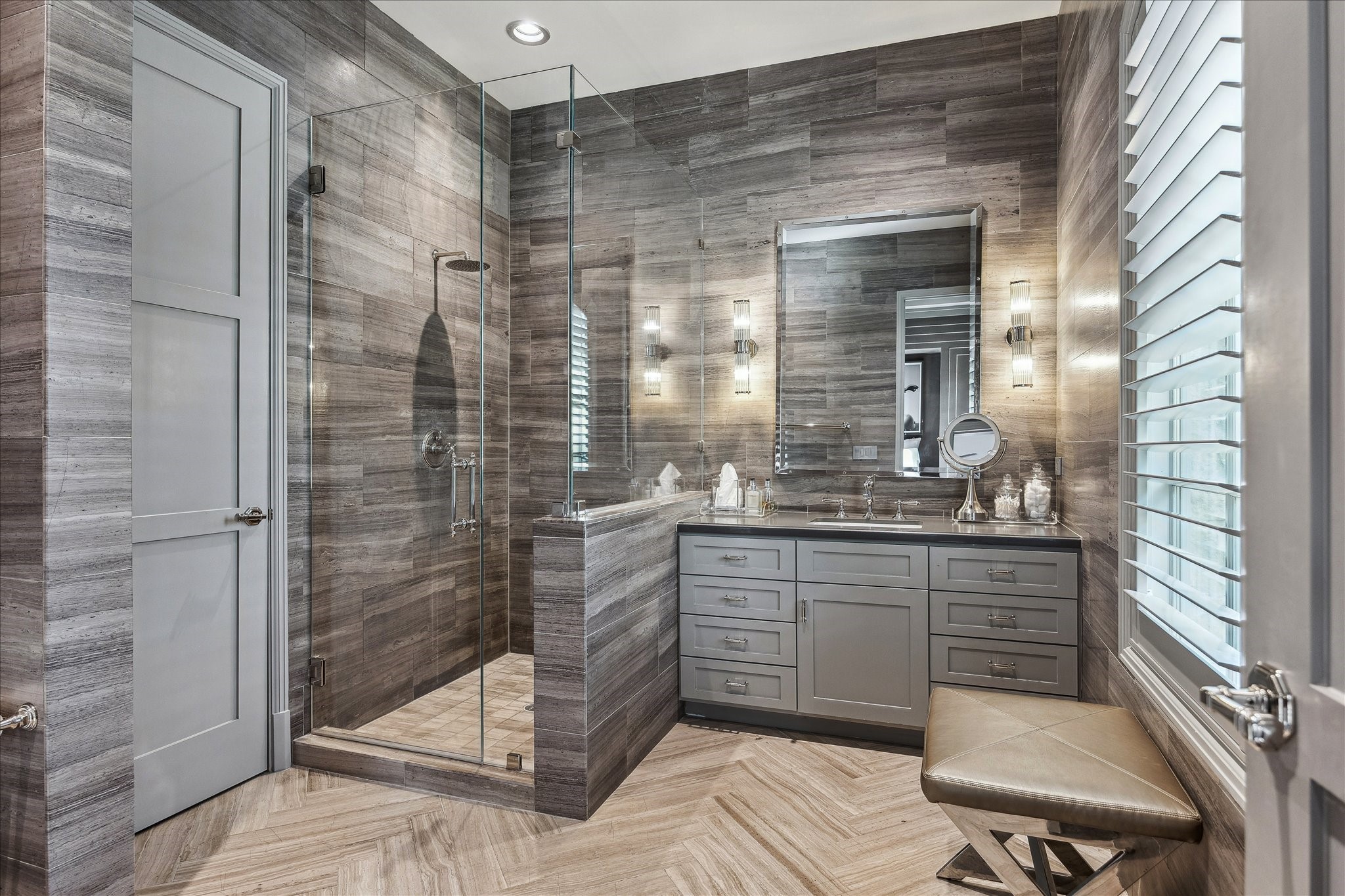 220 Merrie Way Lane Houston, TX 77024 - Photo 43 of 50 This bright secondary bathroom features herringbone tile floors, a marble vanity, polished-nickel hardware, floating glass shelves, and a frameless glass shower—complete with a well-organized walk-in closet.