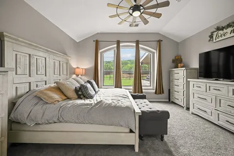 a bedroom with a large bed and a flat tv screen on dresser