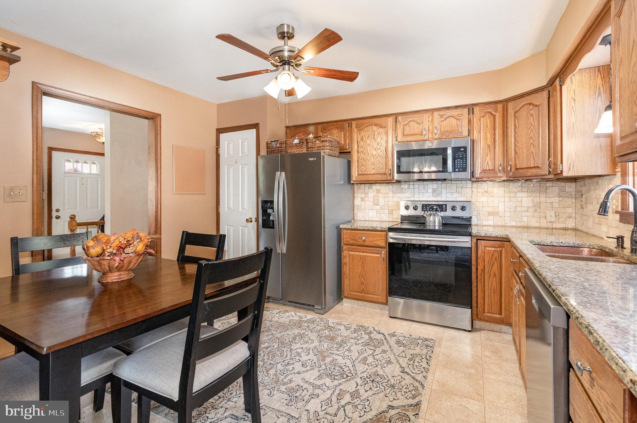 6418 Taunton Road Harrisburg, PA 17111 - Photo 11 of 39 a kitchen with stainless steel appliances granite countertop a stove a refrigerator a sink a dining table and chairs