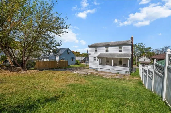 a view of house with yard and trees in the background