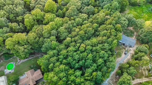 an aerial view of residential house with outdoor space and trees all around