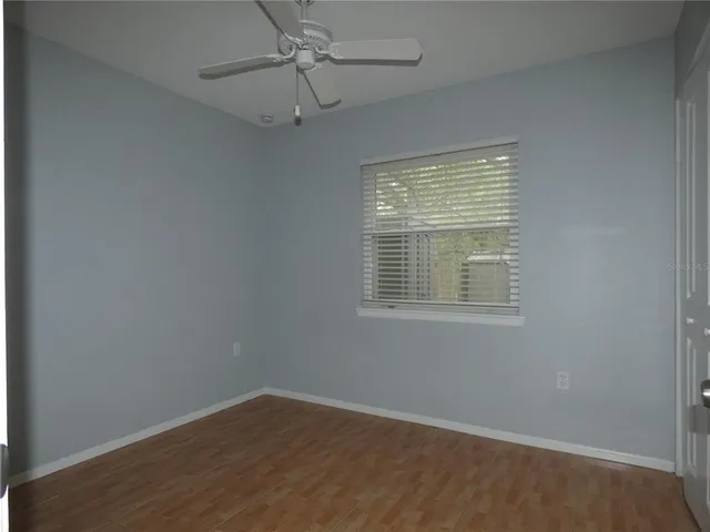 an empty room with wooden floor chandelier fan and windows