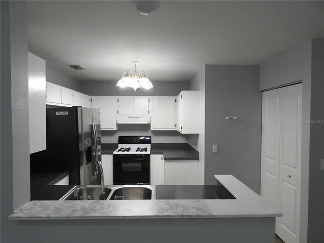 a kitchen with a sink stainless steel appliances a refrigerator and a stove