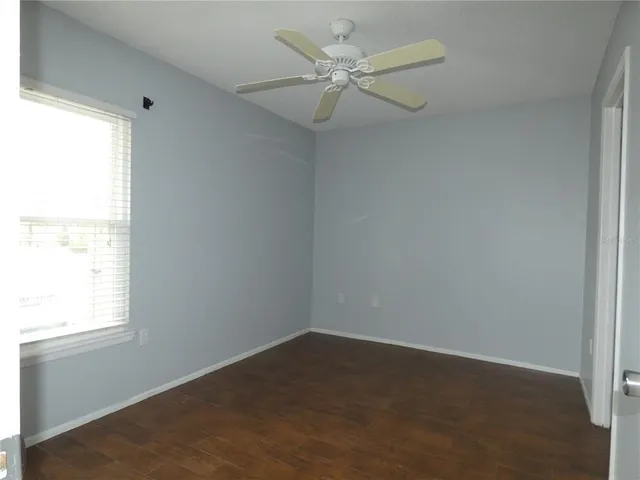 an empty room with a window and a fan
