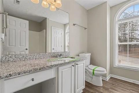 4108 Robin Circle Atlanta, GA 30349 - Photo 3 of 9 a bathroom with a granite countertop sink toilet and large mirror