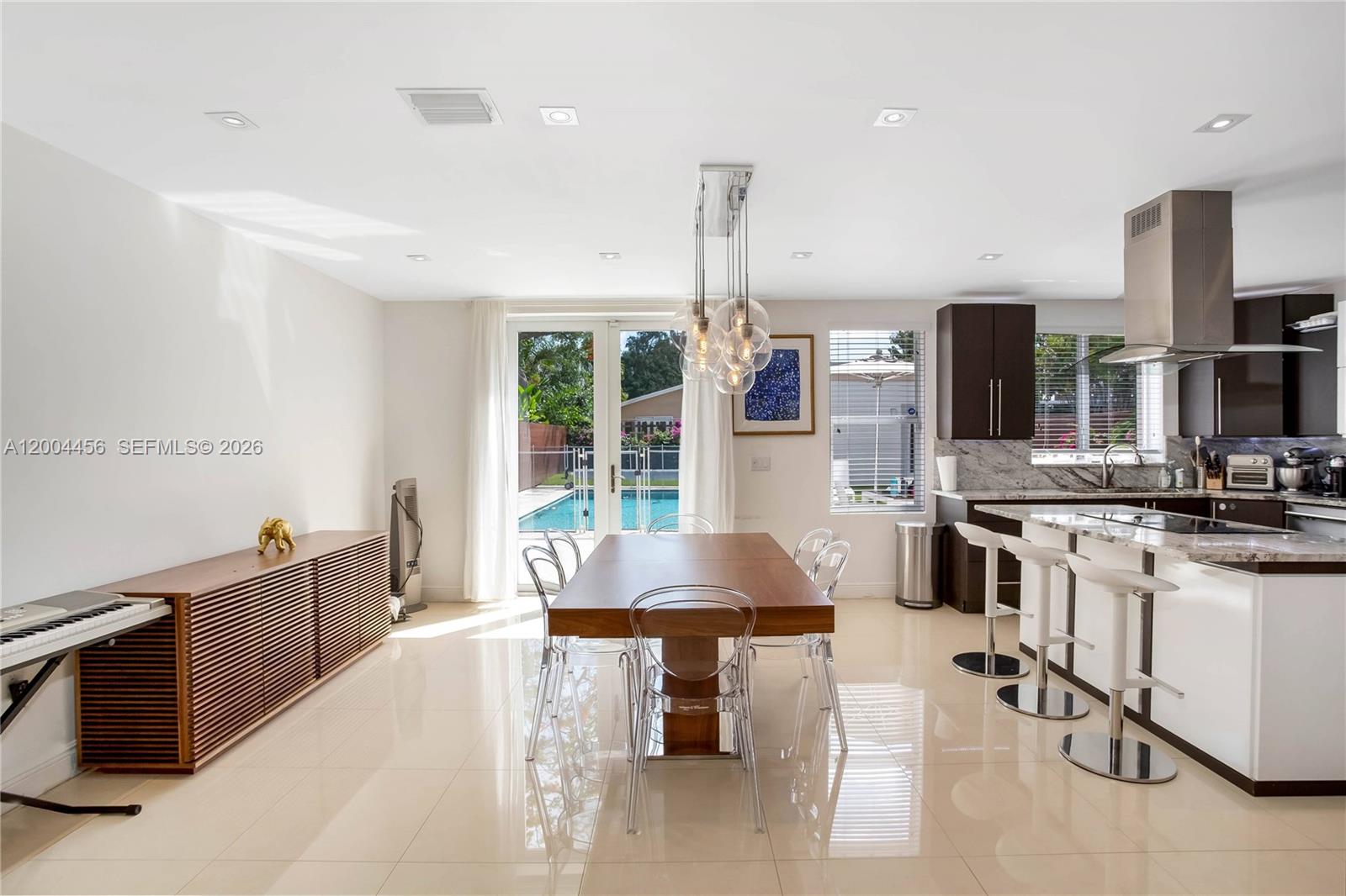 152 Southwest 20th Road Miami, FL 33129 - Photo 9 of 22 a kitchen with stainless steel appliances kitchen island granite countertop a table chairs sink and cabinets