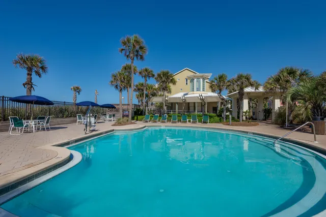 a view of a swimming pool with lawn chairs under an umbrella