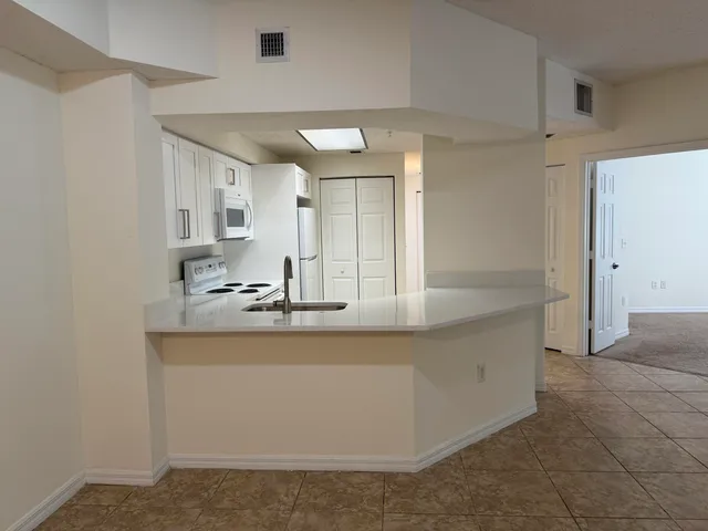 a large kitchen with stainless steel appliances a sink and a refrigerator