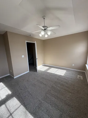 an empty room with windows and fan