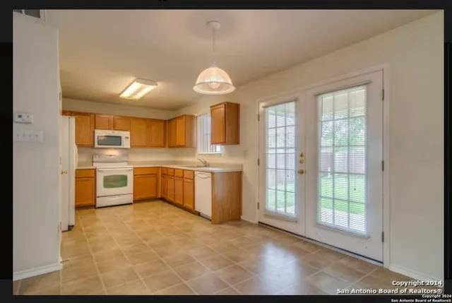 a large kitchen with stainless steel appliances granite countertop a stove a sink dishwasher and a refrigerator with wooden floor