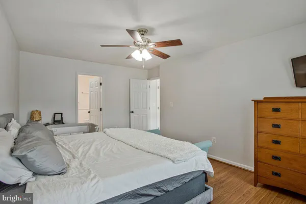 a bedroom with a bed and a dresser with wooden floor