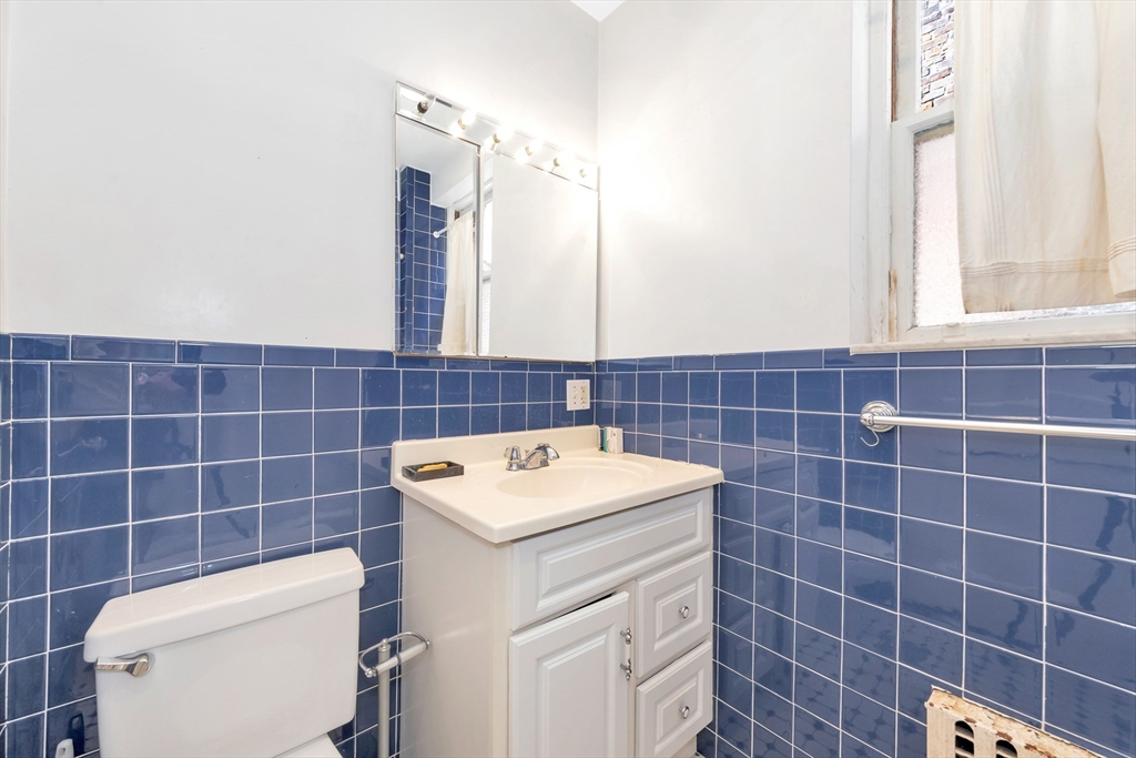 104 Strathmore Road Boston, MA 02135 - Photo 28 of 41 a bathroom with a toilet a sink and a mirror