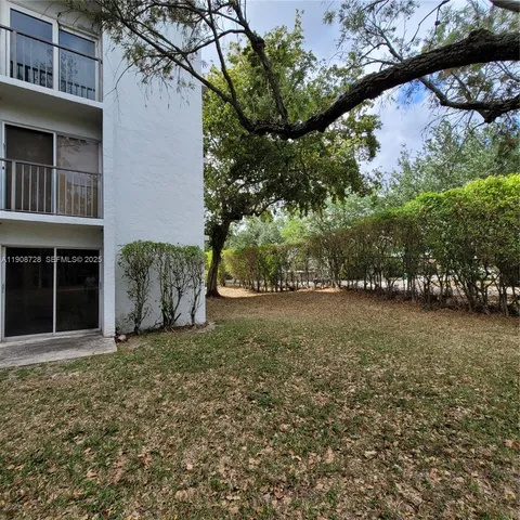 a view of white house with large windows and plants