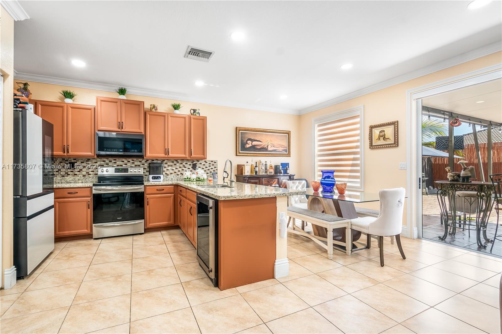4170 Northeast 20th Street Homestead, FL 33033 - Photo 10 of 52 a kitchen with stainless steel appliances kitchen island granite countertop a stove a sink a dining table and chairs