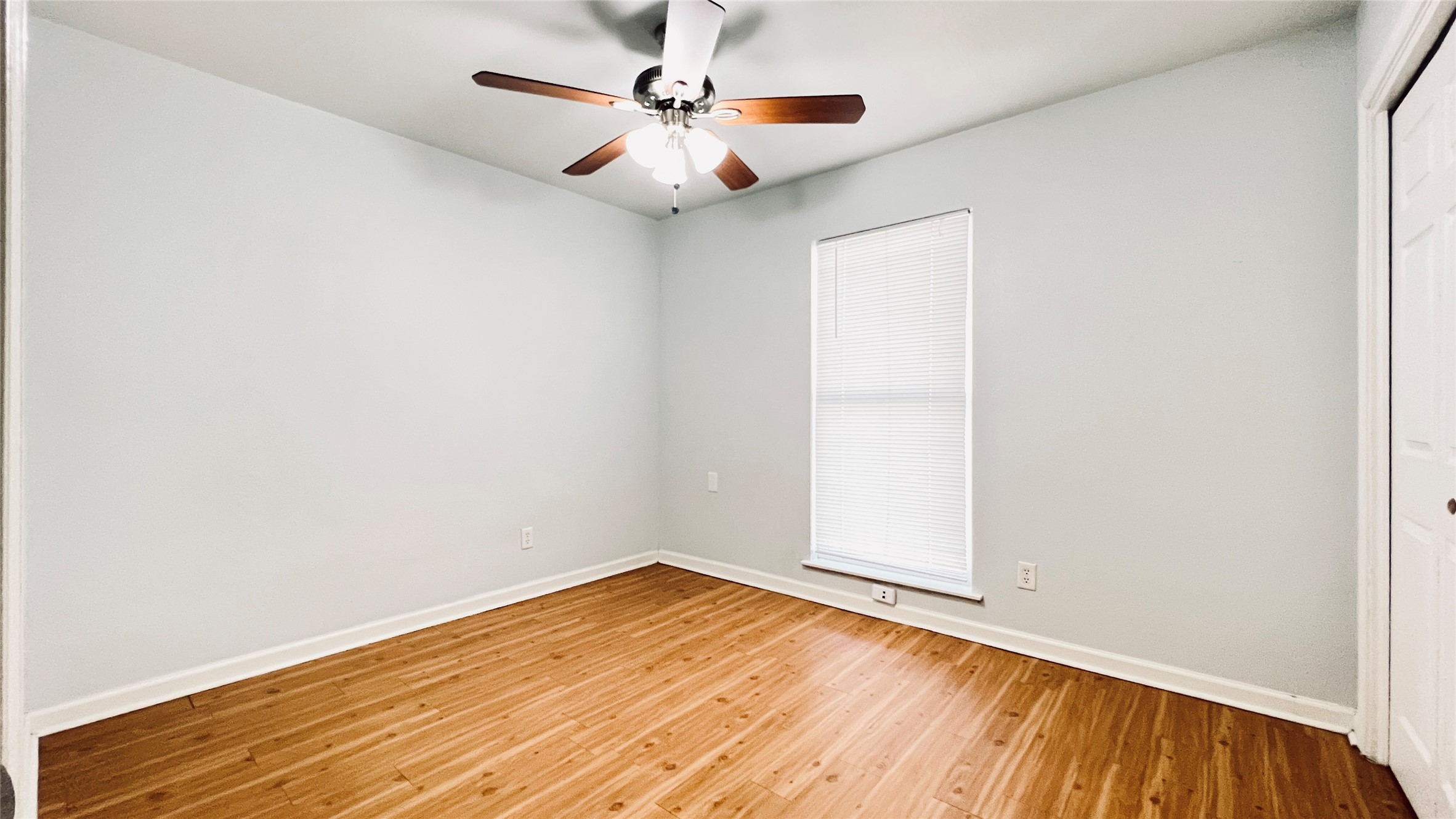 2301 Ohlen Road, Unit 209 Austin, TX 78757 - Photo 5 of 10 A cozy bedroom features a wood-bladed ceiling fan and luminous hardwood flooring.
