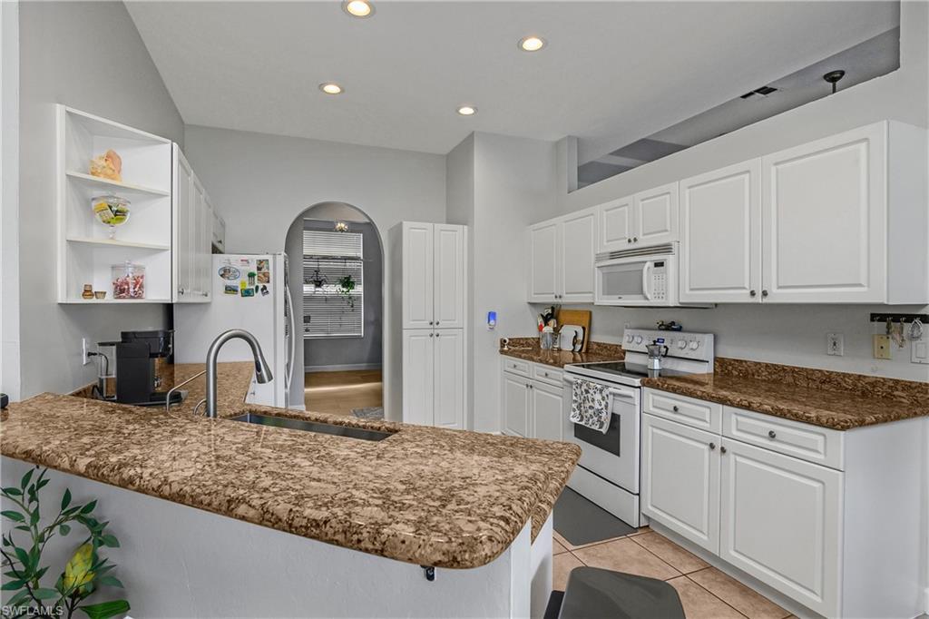 6175 Green Boulevard Naples, FL 34116 - Photo 3 of 20 a kitchen with granite countertop a sink stainless steel appliances and white cabinets