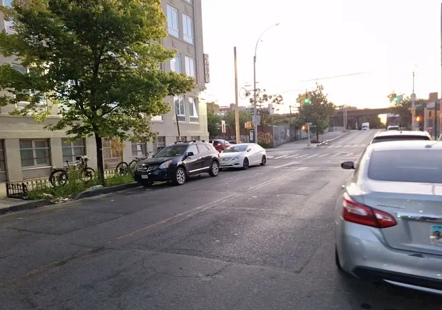 a view of a city street with a couple of cars parked in front of it