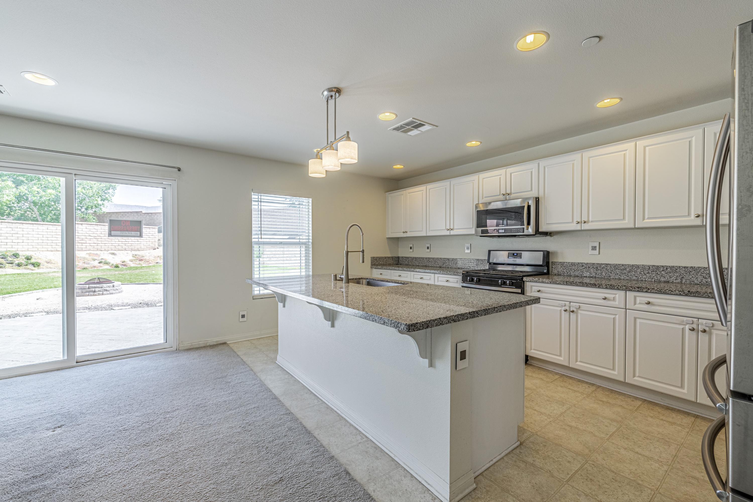 2732 Hemlock Road Palmdale, CA 93551 - Photo 6 of 42 a kitchen with stainless steel appliances granite countertop a stove a sink a refrigerator and white cabinets with wooden floor
