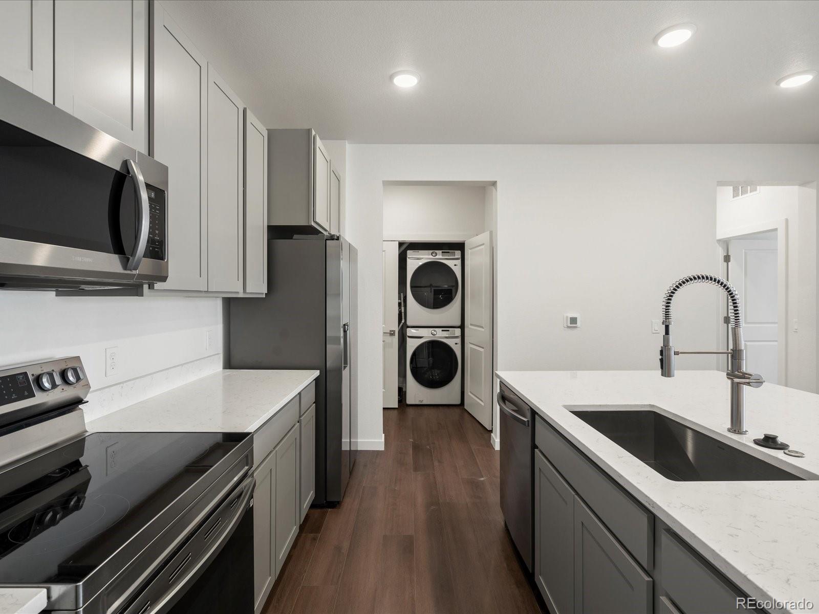 6153 North Ceylon Street, Unit 304 Denver, CO 80249 - Photo 4 of 24 a kitchen with stainless steel appliances kitchen island a sink stove and cabinets