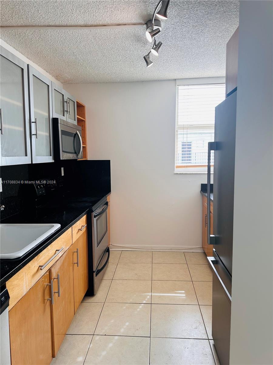 1250 Alton Road, Unit 5F Miami Beach, FL 33139 - Photo 12 of 27 a kitchen with a sink a refrigerator and cabinets