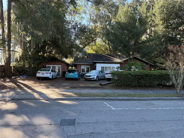 a front view of a house with a garden and trees