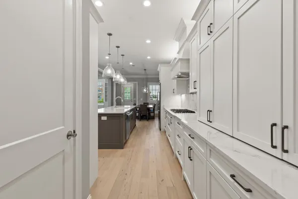 a large white kitchen with a lot of counter space and a wooden floor