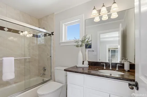 a bathroom with a granite countertop sink a toilet a mirror a vanity a shower and vanity
