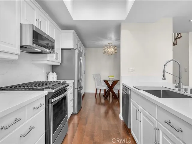 a kitchen with granite countertop a sink a stove and wooden floors