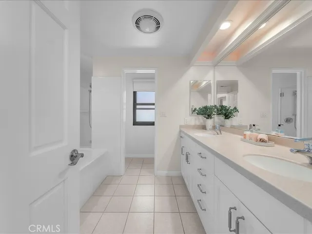 a spacious bathroom with a double vanity sink a mirror and a bathtub