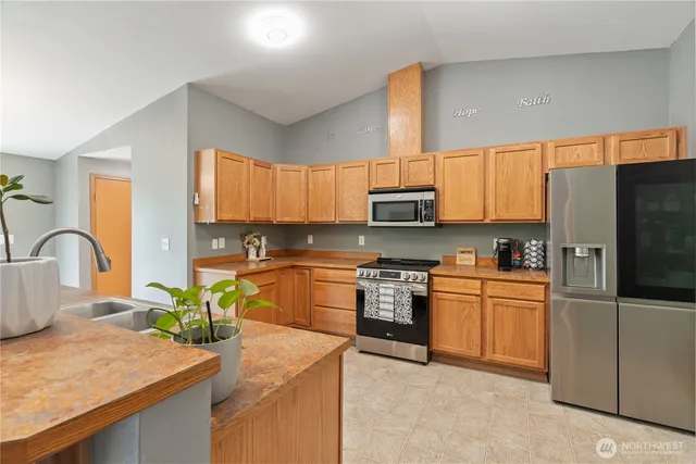 a kitchen with stainless steel appliances granite countertop a refrigerator sink stove microwave and cabinets