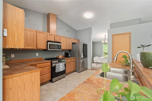 a kitchen with stainless steel appliances granite countertop a stove top oven a sink dishwasher a dining table and chairs with wooden floor