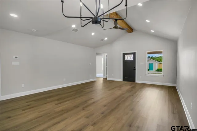 a view of an empty room with window and wooden floor