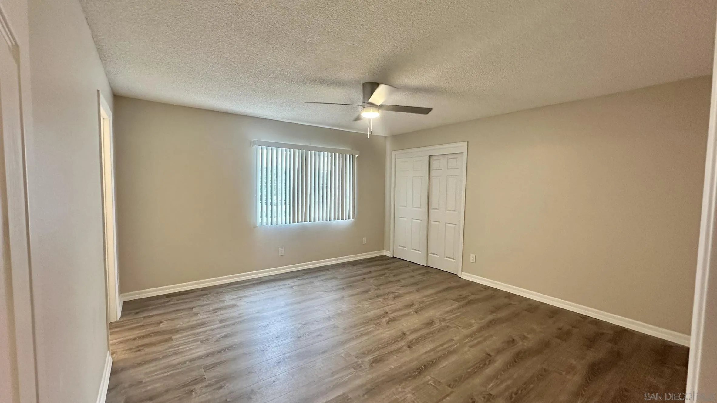 16142 Dartolo Road Ramona, CA 92065 - Photo 13 of 31 an empty room with wooden floor ceiling fan and windows