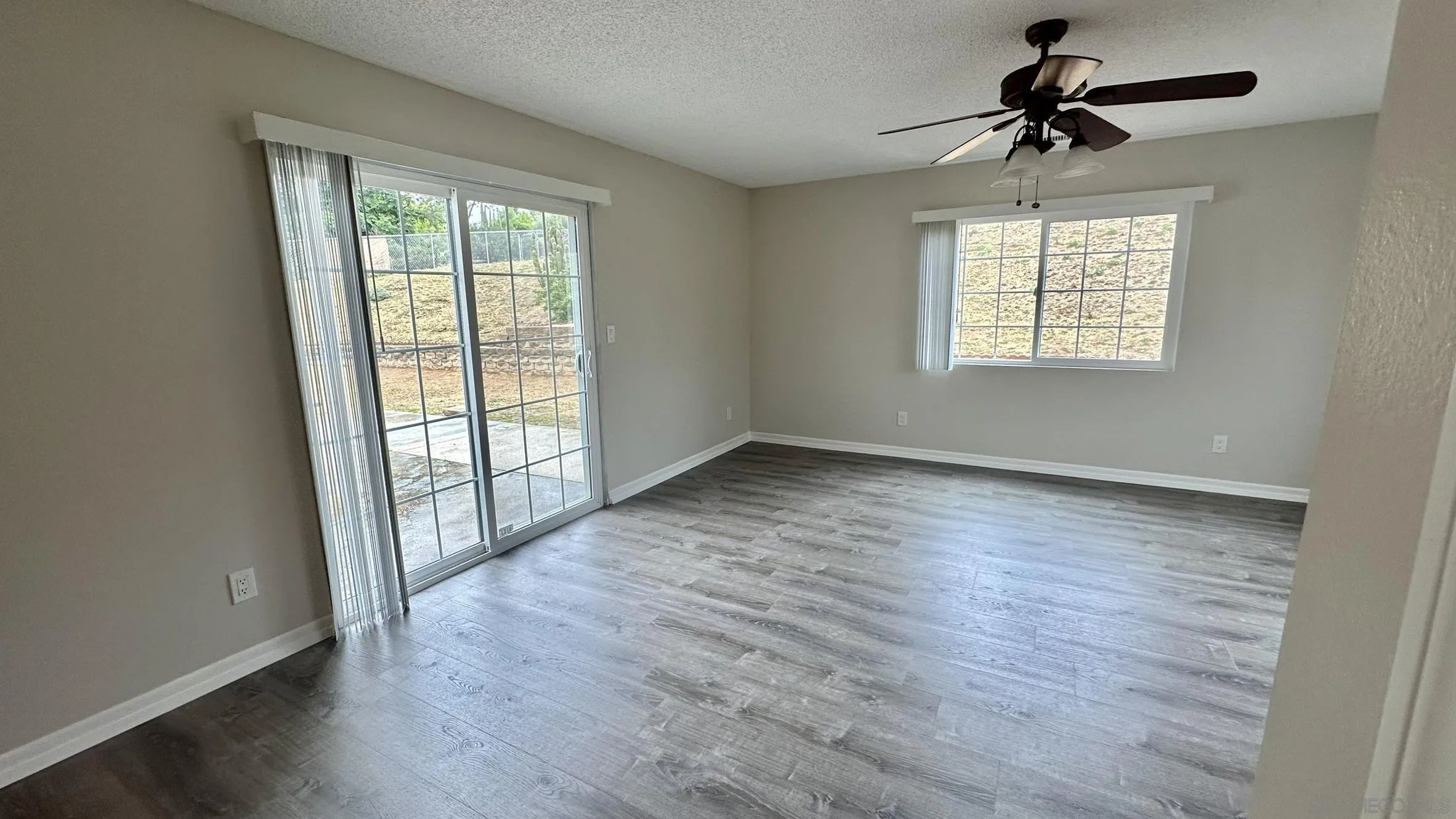16142 Dartolo Road Ramona, CA 92065 - Photo 20 of 31 an empty room with wooden floor chandelier fan and windows