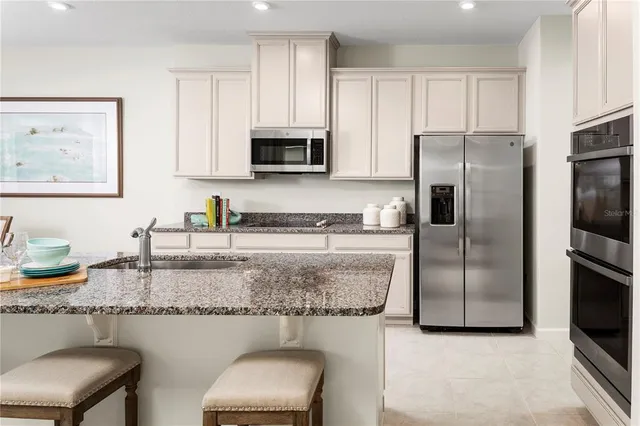 a kitchen with stainless steel appliances granite countertop a sink refrigerator and microwave