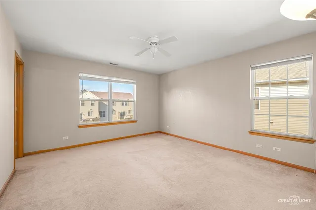 an empty room with windows and ceiling fan